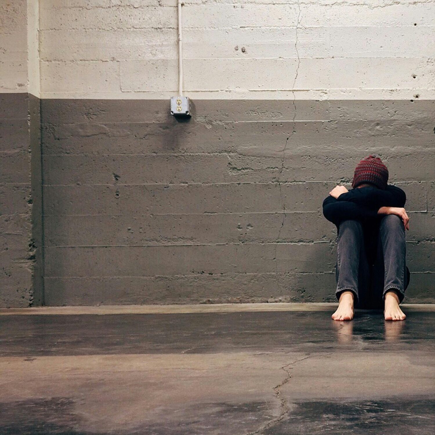A person sitting alone in a corner, evoking themes of solitude and emotion.